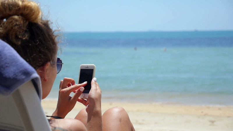 Menina com celular na praia